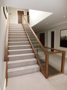 walnut staircase, cream carpet, glass balustrade