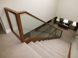 walnut staircase, cream carpet, glass balustrade