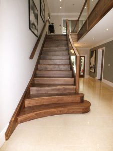curved walnut staircase, glass balustrade