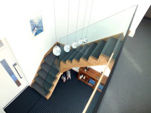 oak staircase with glass and blue carpet