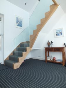 oak staircase with glass and blue carpet