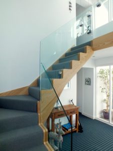 oak staircase with glass and blue carpet