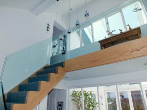 oak staircase with glass and blue carpet