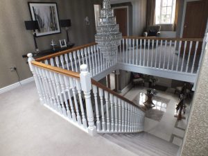 white staircase, oak handrail and bottom step, chandelier