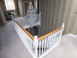 white staircase, oak handrail and bottom step, chandelier