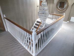 white staircase, oak handrail and bottom step, chandelier