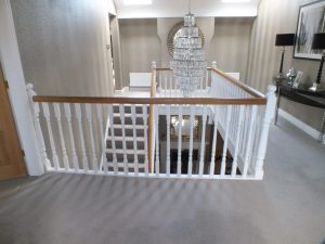 white staircase, oak handrail and bottom step, chandelier